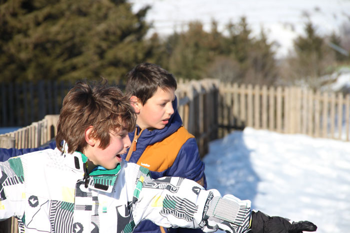 Deux enfants regardent le bas d'une pente à la neige