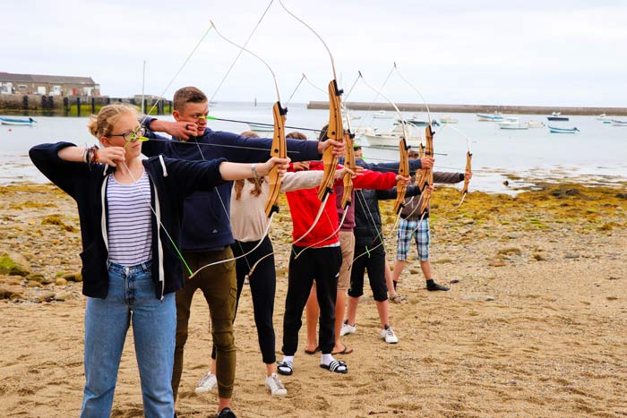 Une séance de tir à l'arc sur la plage durant une colonie ado